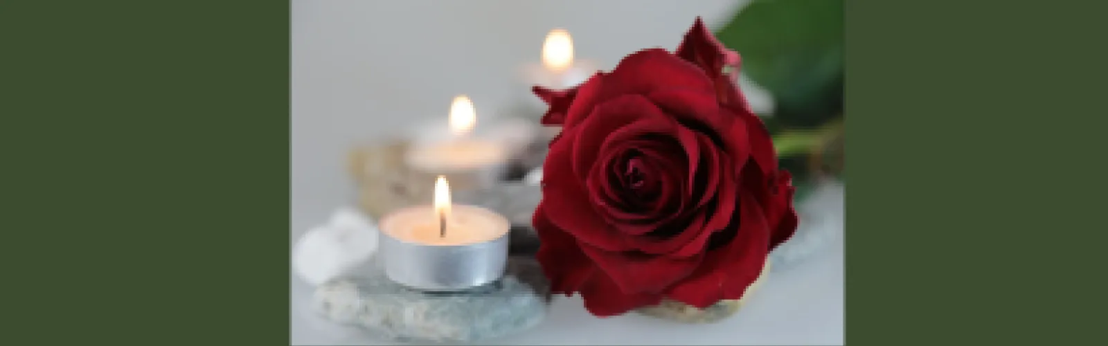Red rose next to a candle on a green background