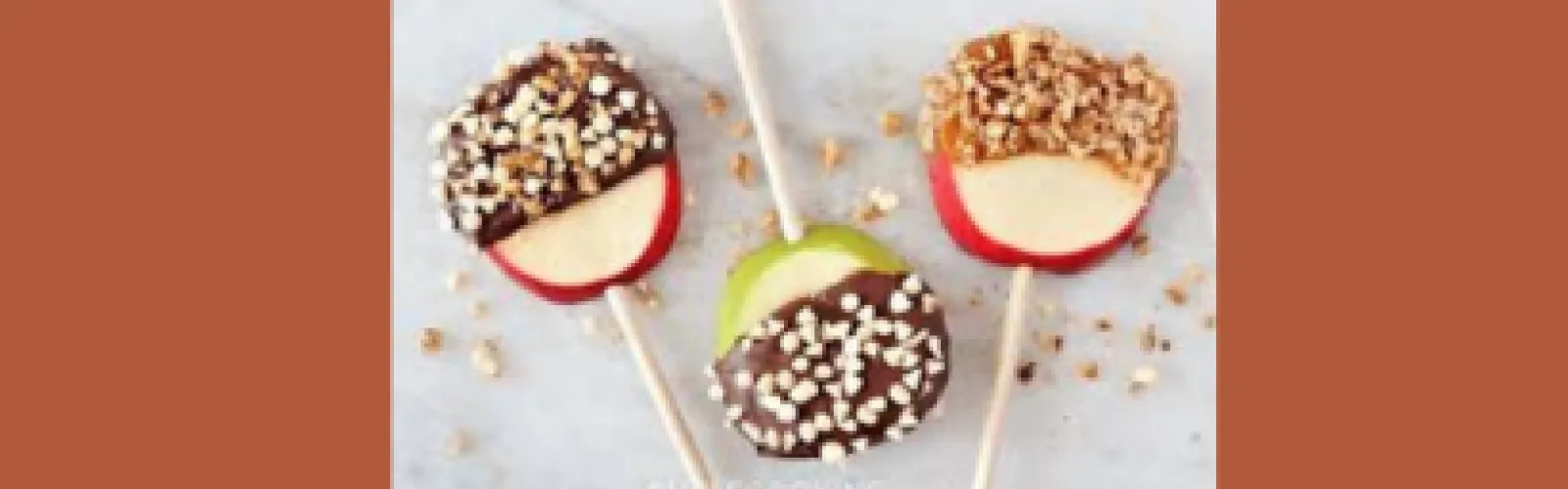 Three carmel apple slices covered with nuts on a brown background