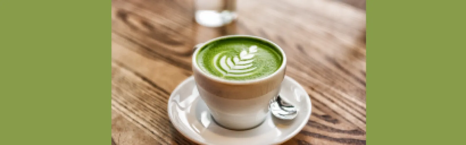 A tea cup with matcha tea and latte art on a green background