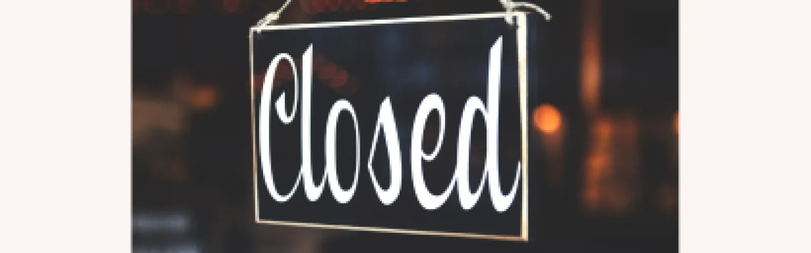 Closed sign on a door with a dark background with some lights