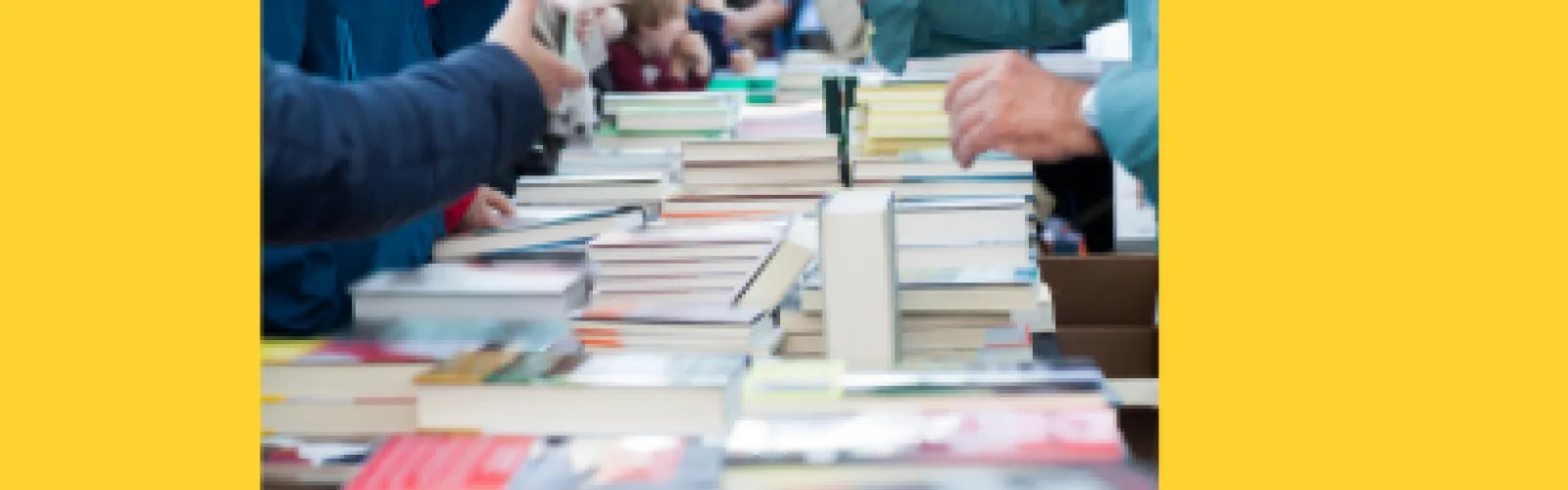 Table full of books and arms reaching for the books