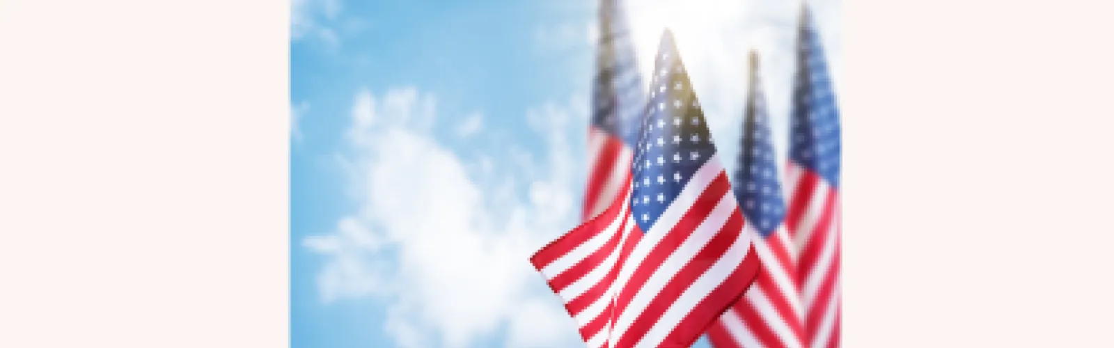 Five U.S. flags on light blue sky background on beige background