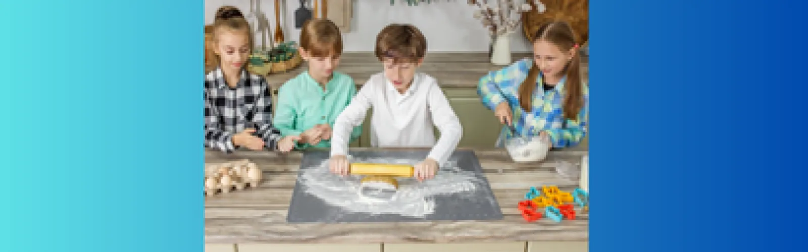 Four children standing around a boy who is rolling out dough to bake cookies