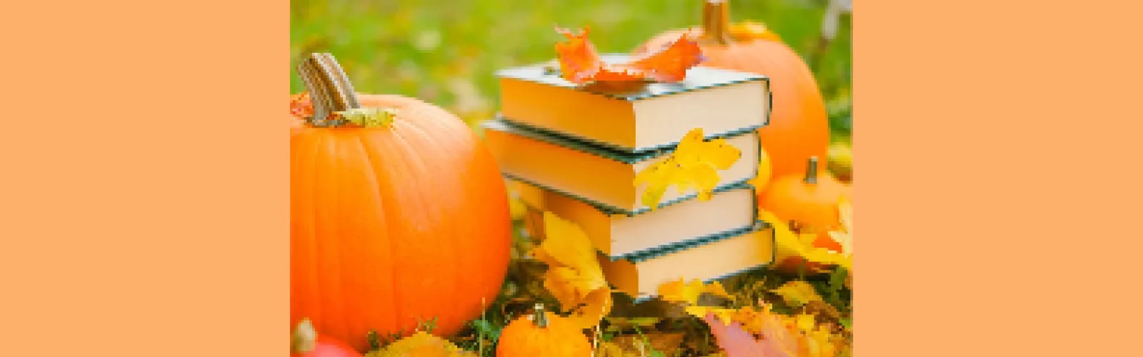 Pumpkins and  a stack of books along with a variety of leaves