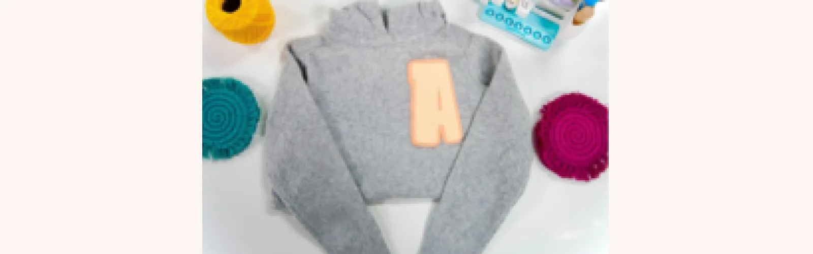 Gray sweater with a peach letter A patch on the right side