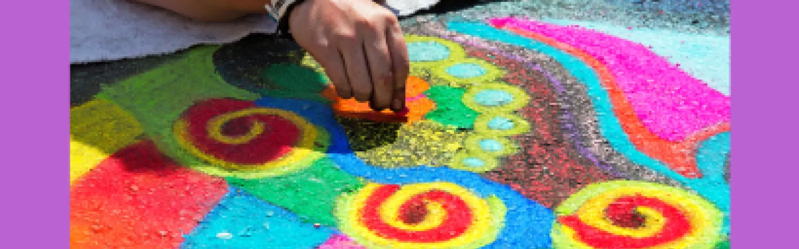 Hand creating a colorful chalk art design