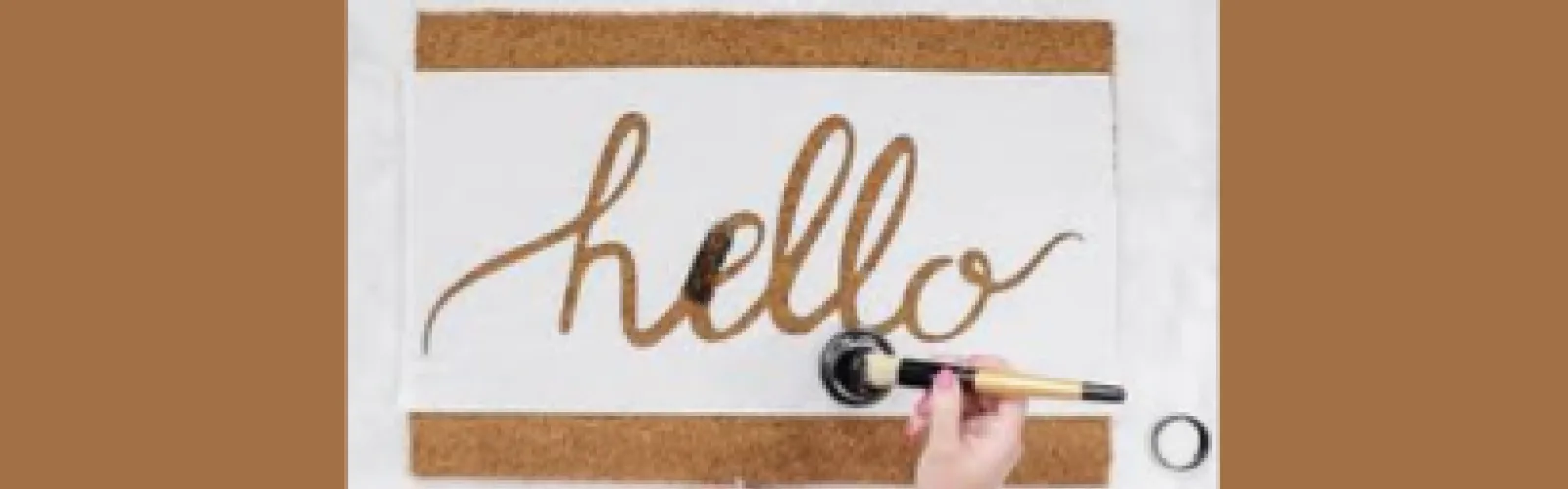 Hand painting the word hello on a welcome mat