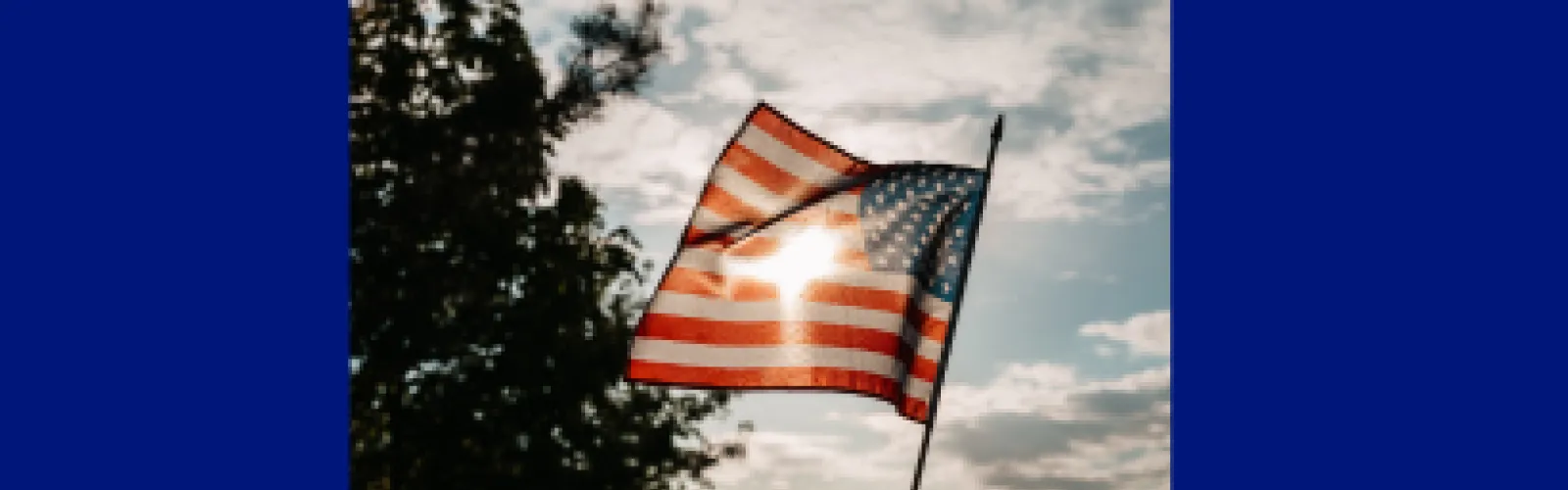 United States flag blowing in the wind with the sun shining through it