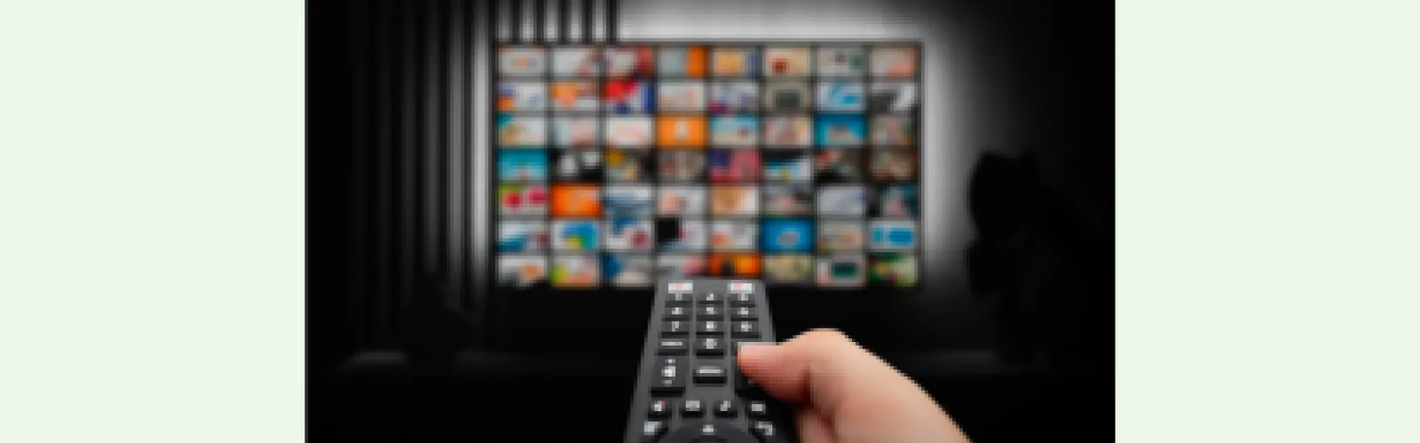 A television screen of apps with hand pointing a remote control toward it