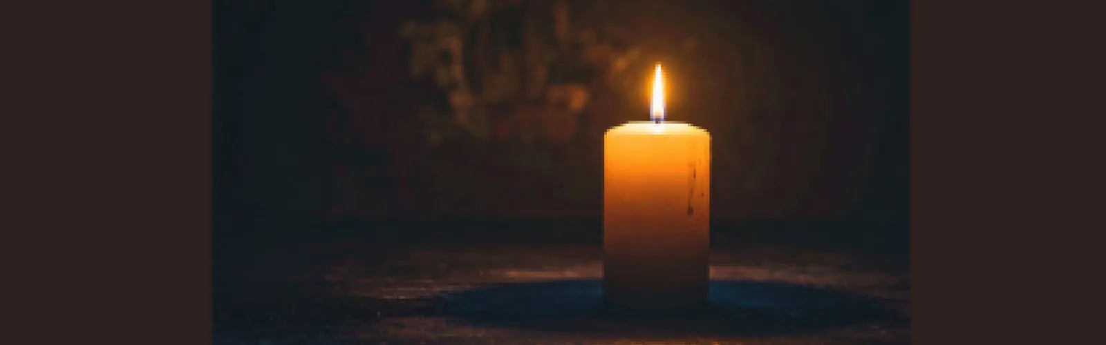 A lit pillar candle on a dark background
